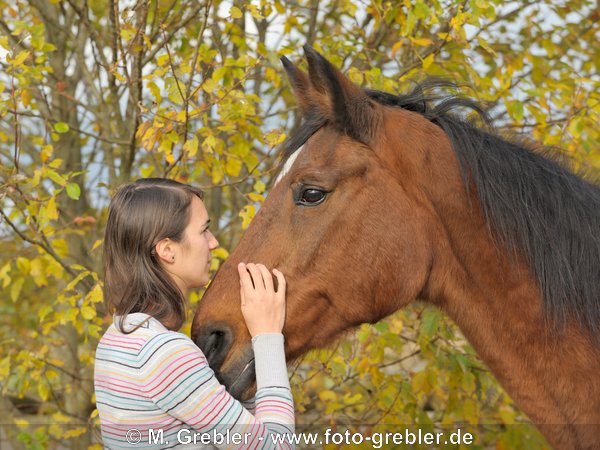 Junge Frau mit ihrer alten Hannoveraner Stute 