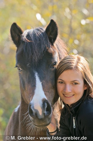 Frau beim Schmusen mit Pony im Herbst 