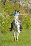 Zwei junge Reiterinnen galoppieren zusammen freihändig auf einem Bayerischen Warmblut 