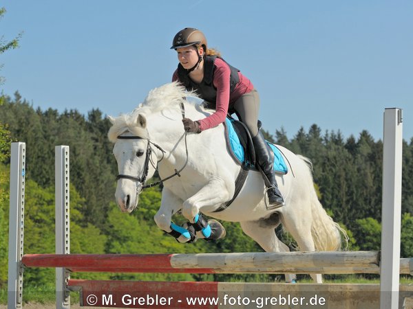 Junge Reiterin mit Sicherheitsweste beim Springen mit Deutschem Reitpony 