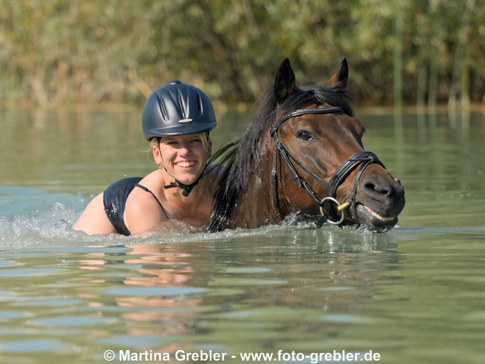 Junge Frau beim Baden mit Reitpony 