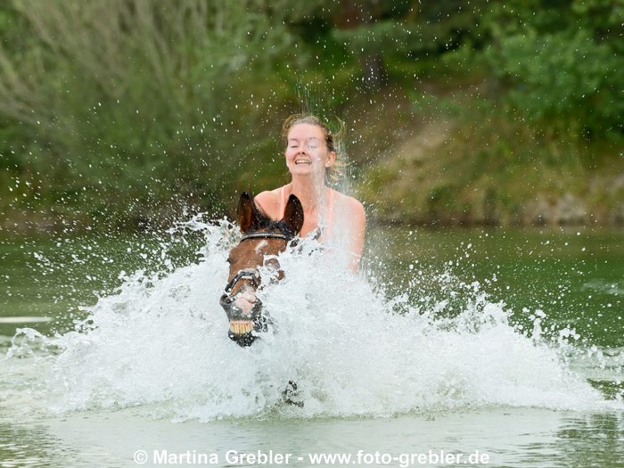 Frau beim Baden mit ihrem Pony 