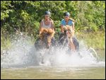 Zwei junge Reiternnen auf Isländern galoppieren in der Isar südlich von München