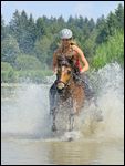 Jugendliche Reiterin auf IslÃ¤nder-Stute galoppiert in einem kleinen See in Bayern 